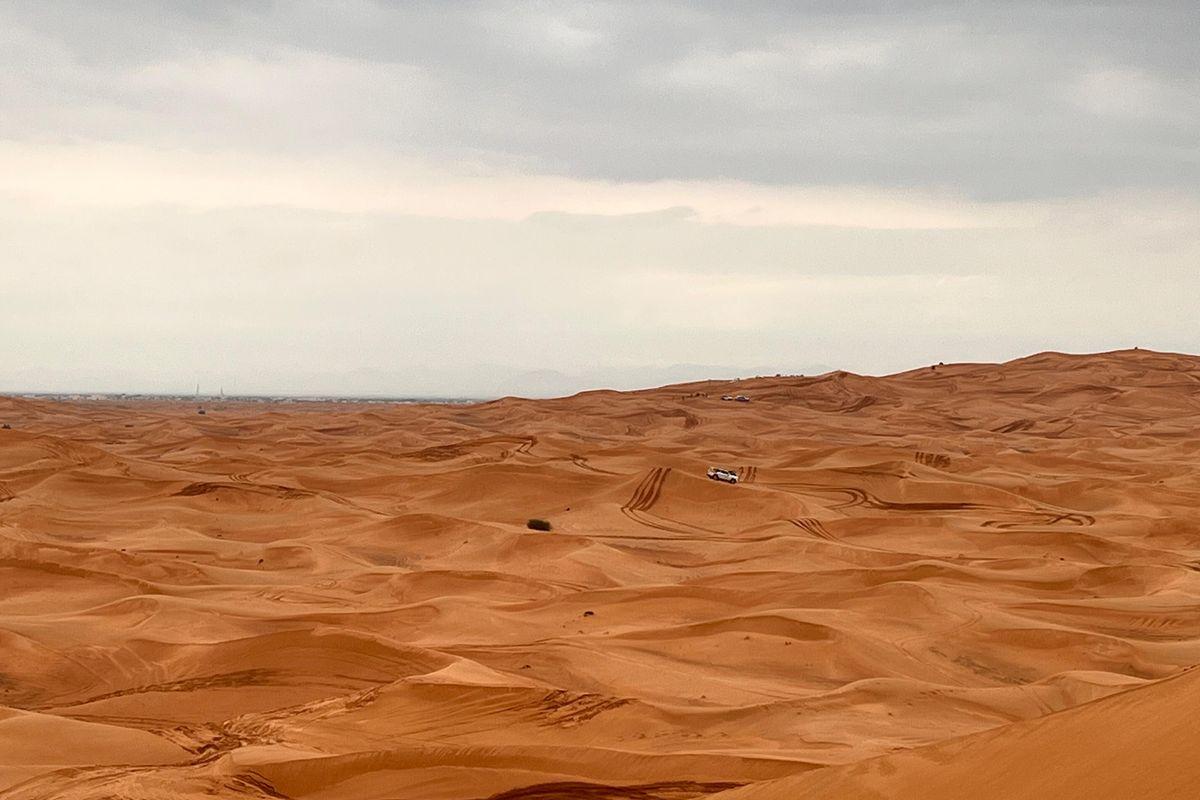 Vast Dubai red sand dunes with tire tracks from self-drive dune buggy adventure
