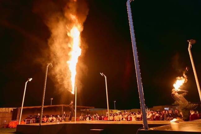 Fire show flames lighting up the desert camp stage at night