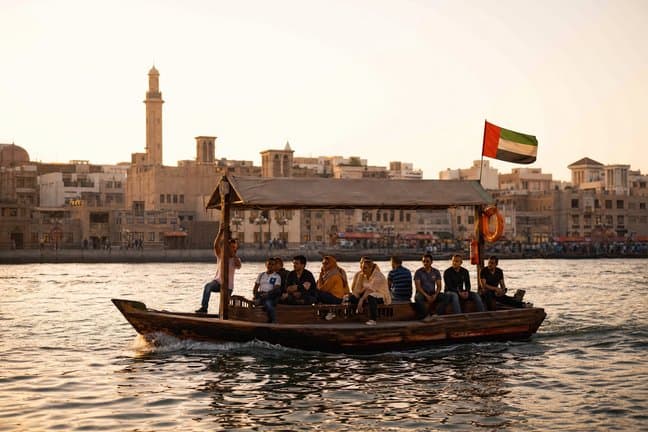 Guests crossing Dubai Creek on a traditional abra boat at sunset