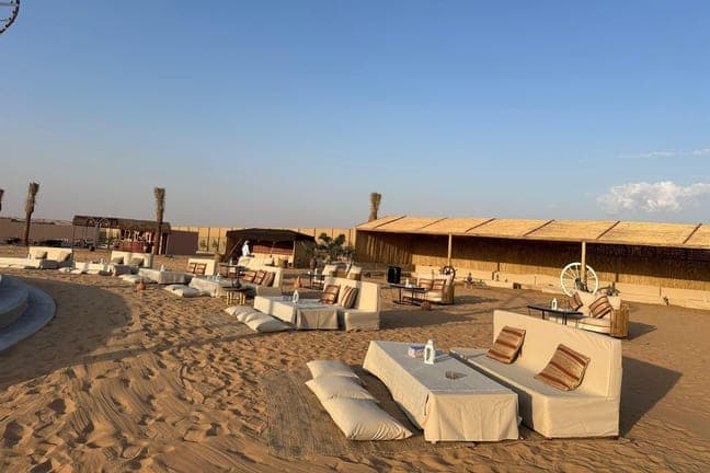 Low Arabic floor seating on the sand at the desert camp before sunset