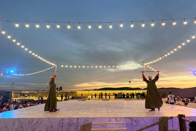 Tanoura performers on the open-air stage at the desert camp at sunset