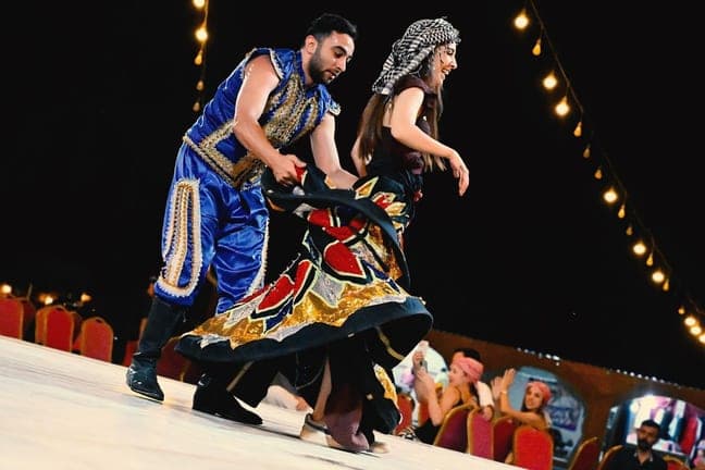 Folk dancers performing a traditional routine at the desert camp