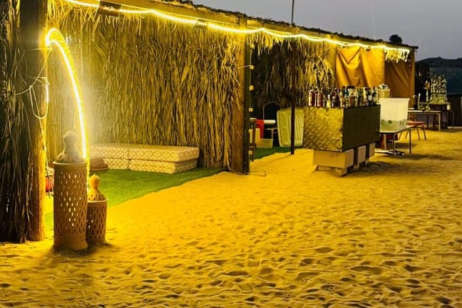Lit reed hut at the desert camp as night falls