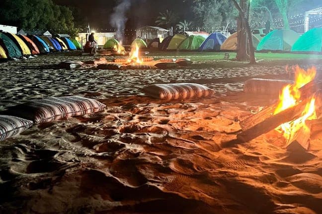Campfire beside overnight camping tents in the Dubai desert