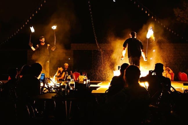 Fire show performers seen from the audience at the desert camp