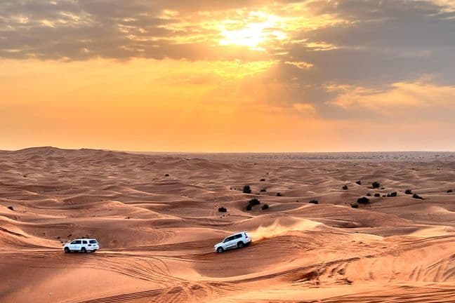 4x4 Land Cruisers dune bashing at sunset in Dubai desert