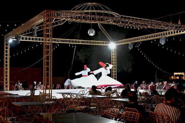 Tanoura dancers spinning on stage at the desert safari camp