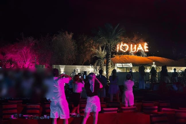 Guests watching the evening show at a lit desert camp in Dubai