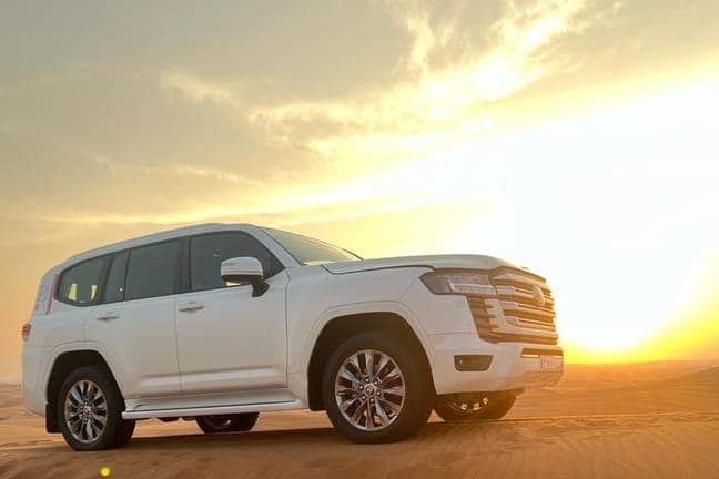 White Land Cruiser on a red dune at sunset in the Dubai desert