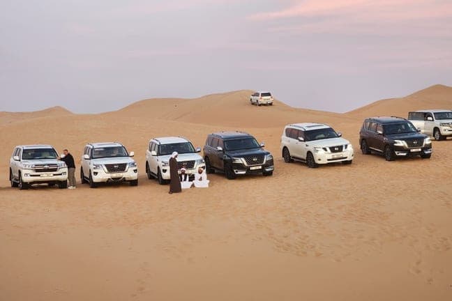 Land Cruisers lined up on the red dunes before dune bashing