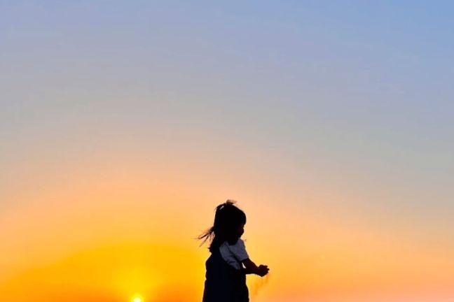 Child silhouette against colorful sunset sky in Dubai desert