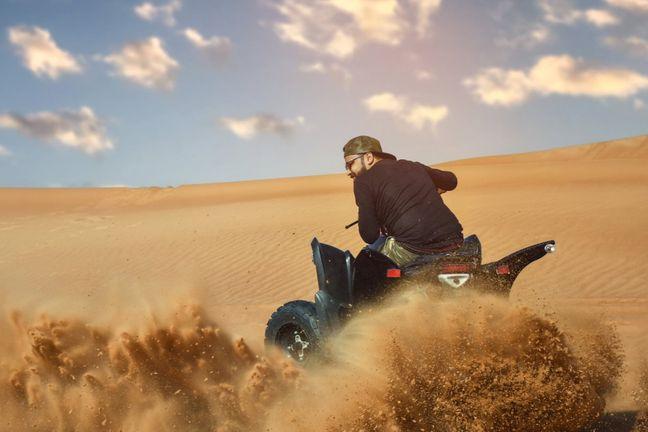 Rider spraying sand on ATV quad bike during Dubai desert safari ride